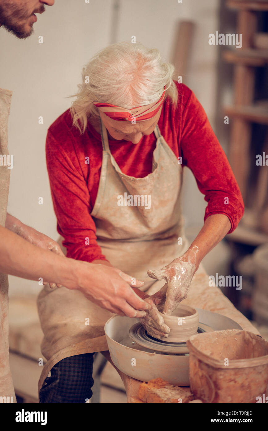 Serious aged woman looking at the pottery wheel Stock Photo