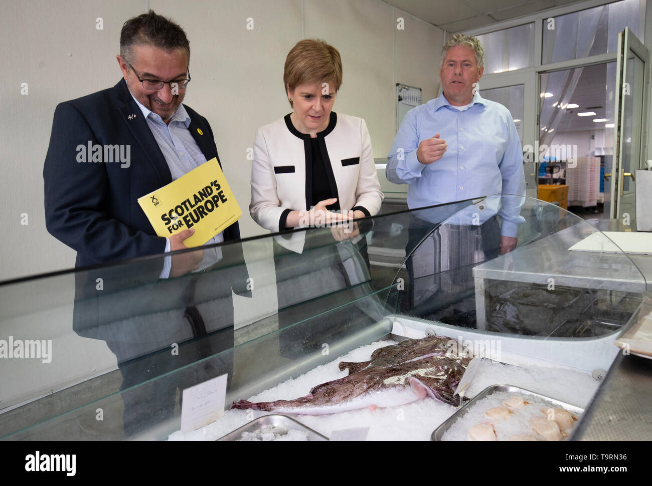 First Minister Nicola Sturgeon with SNP European election candidate Christian Allard (left) and owner Andrew Charles (right) during a visit to J Charles Ltd seafood processing plant in Aberdeen. Christian Allard worked at J Charles Ltd for 25 years exporting seafood to the continent, before he entered politics. Stock Photo