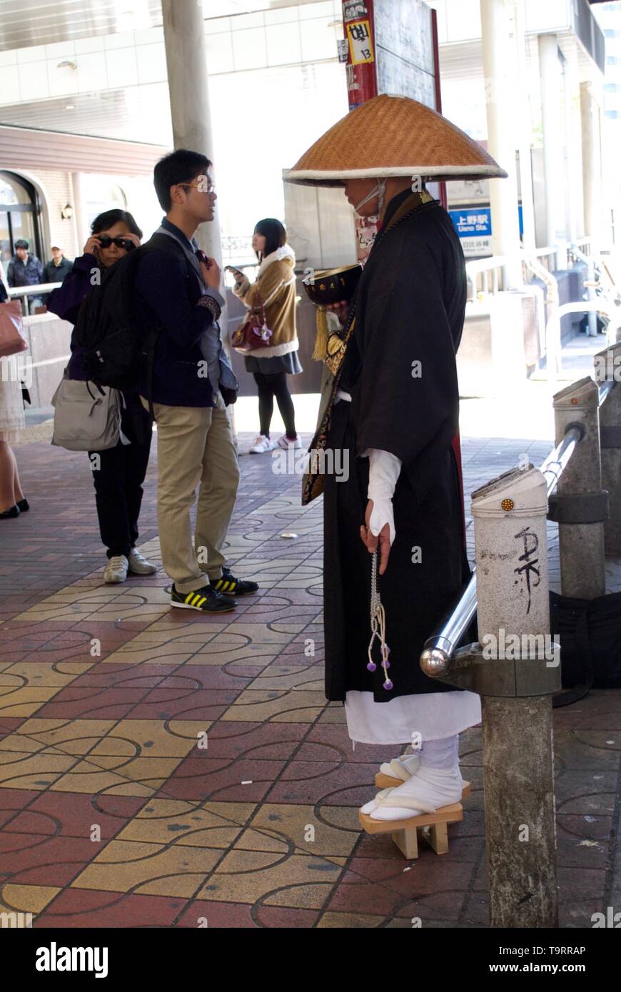 A monk waiting patiently for contributions on a Tokyo street Stock Photo