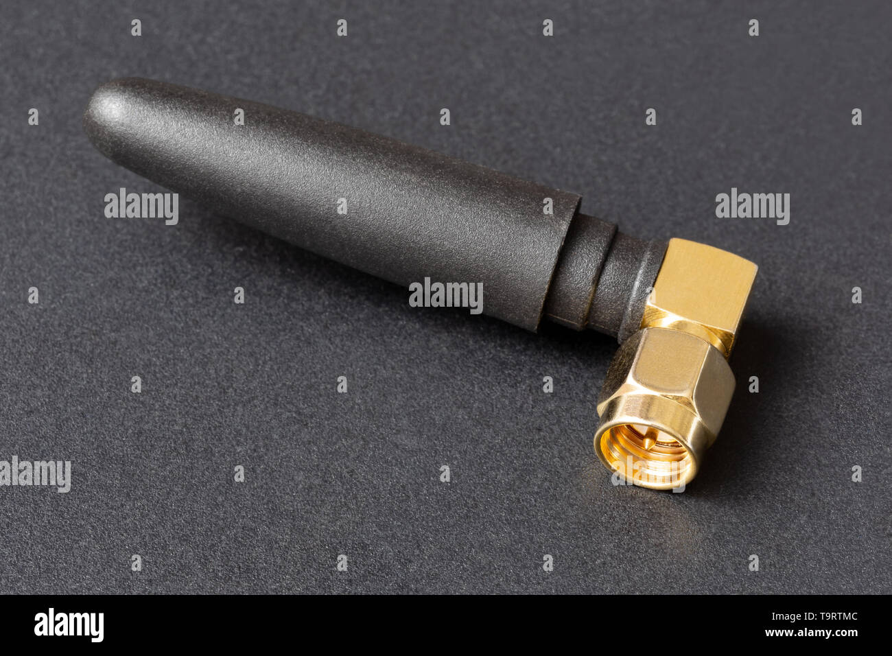 compact Wi-Fi antenna with gold-plated plug on a dark background Stock Photo