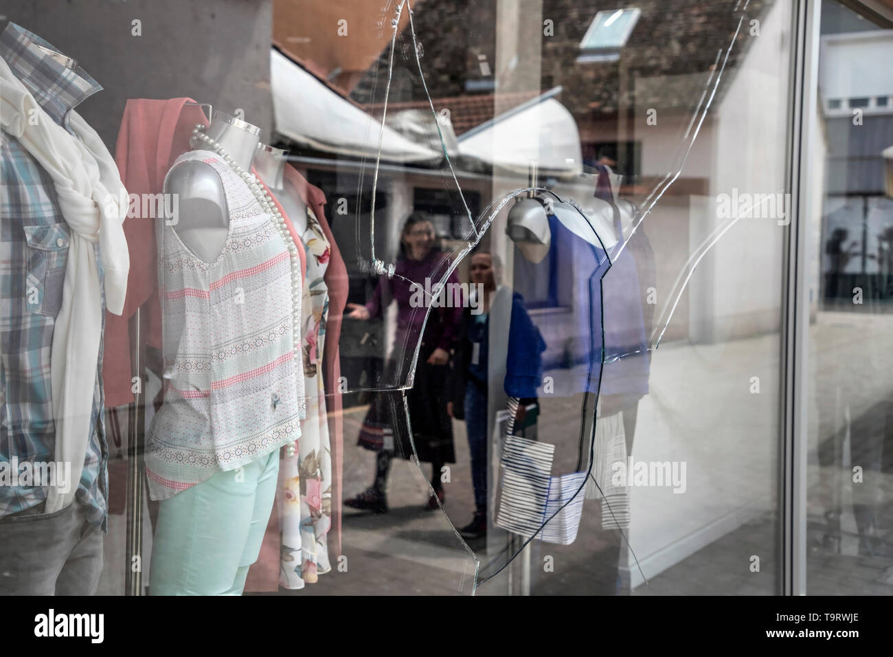 Slavonski Brod, Croatia, May 17th 2019: Downtown scene with showcase of boutiques vandalized and reflection of people walking down the street Stock Photo