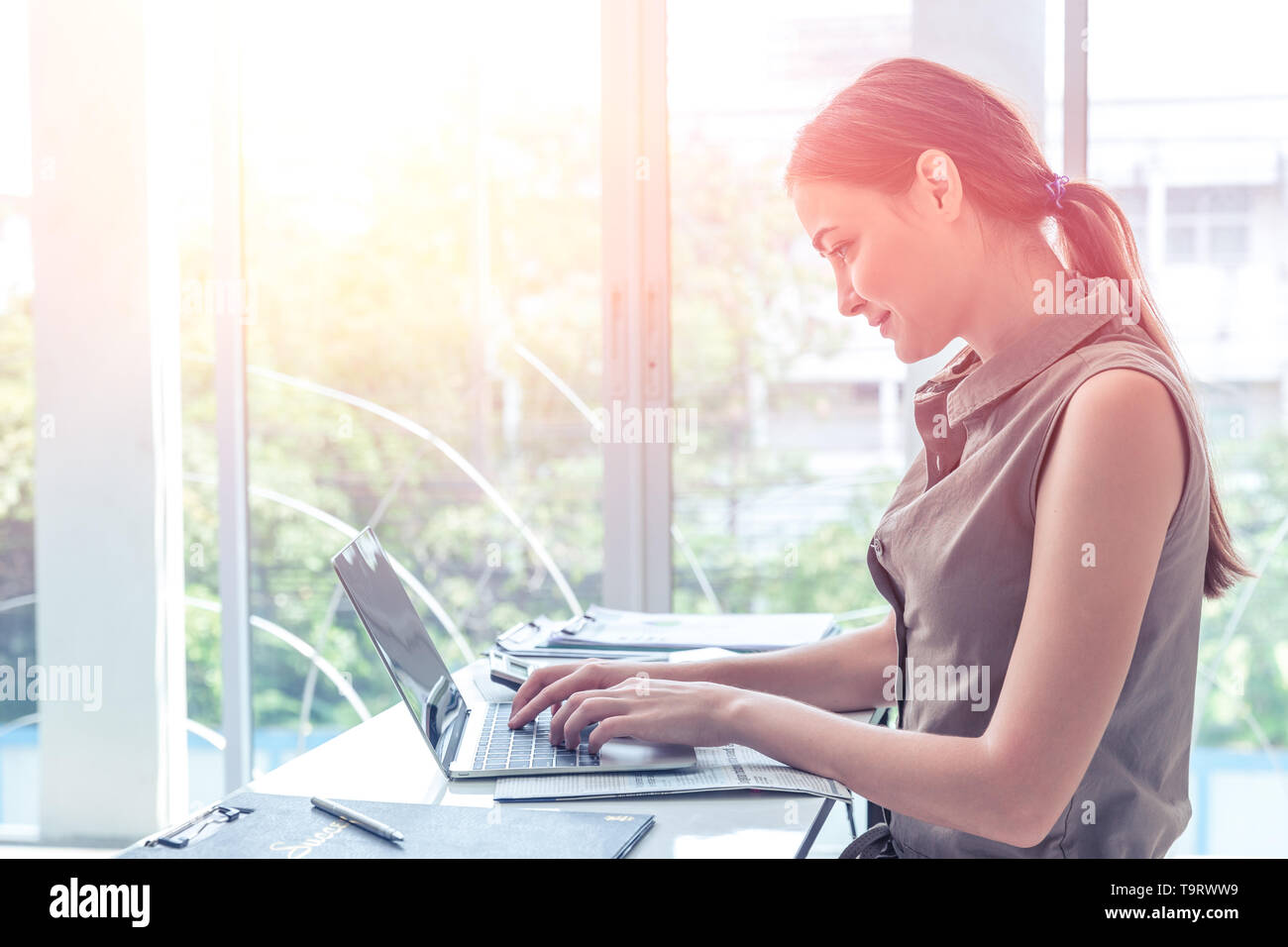 girl work typing on laptop computer business in office windows portait side view Stock Photo