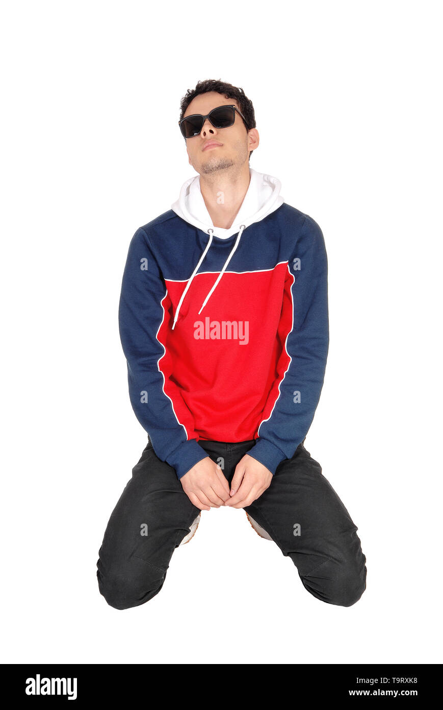 A handsome young man wearing sunglasses kneeling on the floor in sports ...