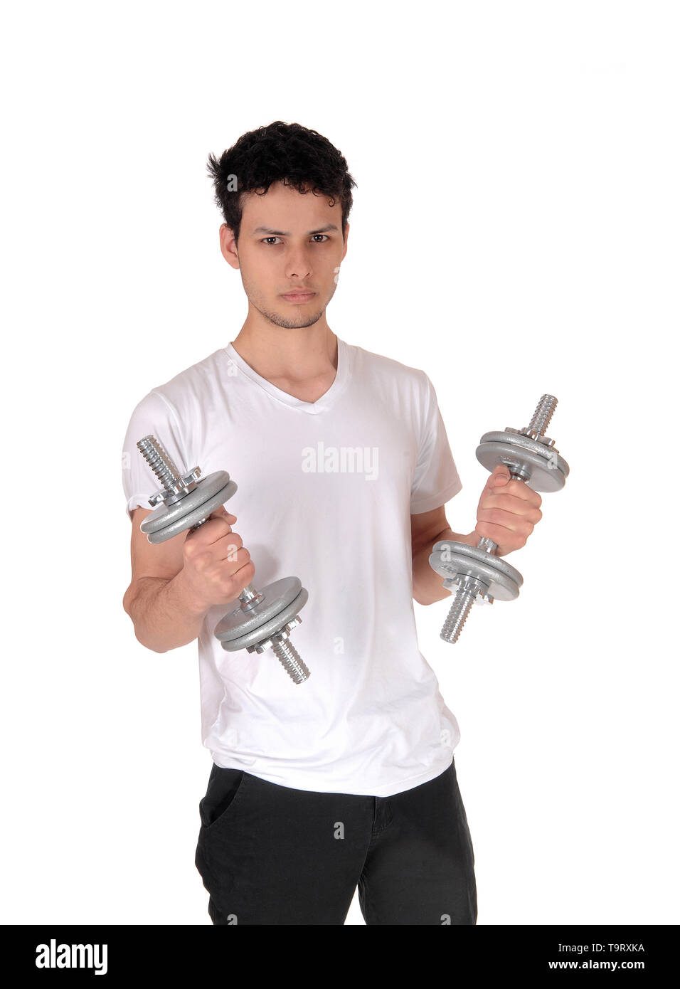 A handsome young man standing in the studio exercising with his two dumbbells, waist up, isolated for white background Stock Photo