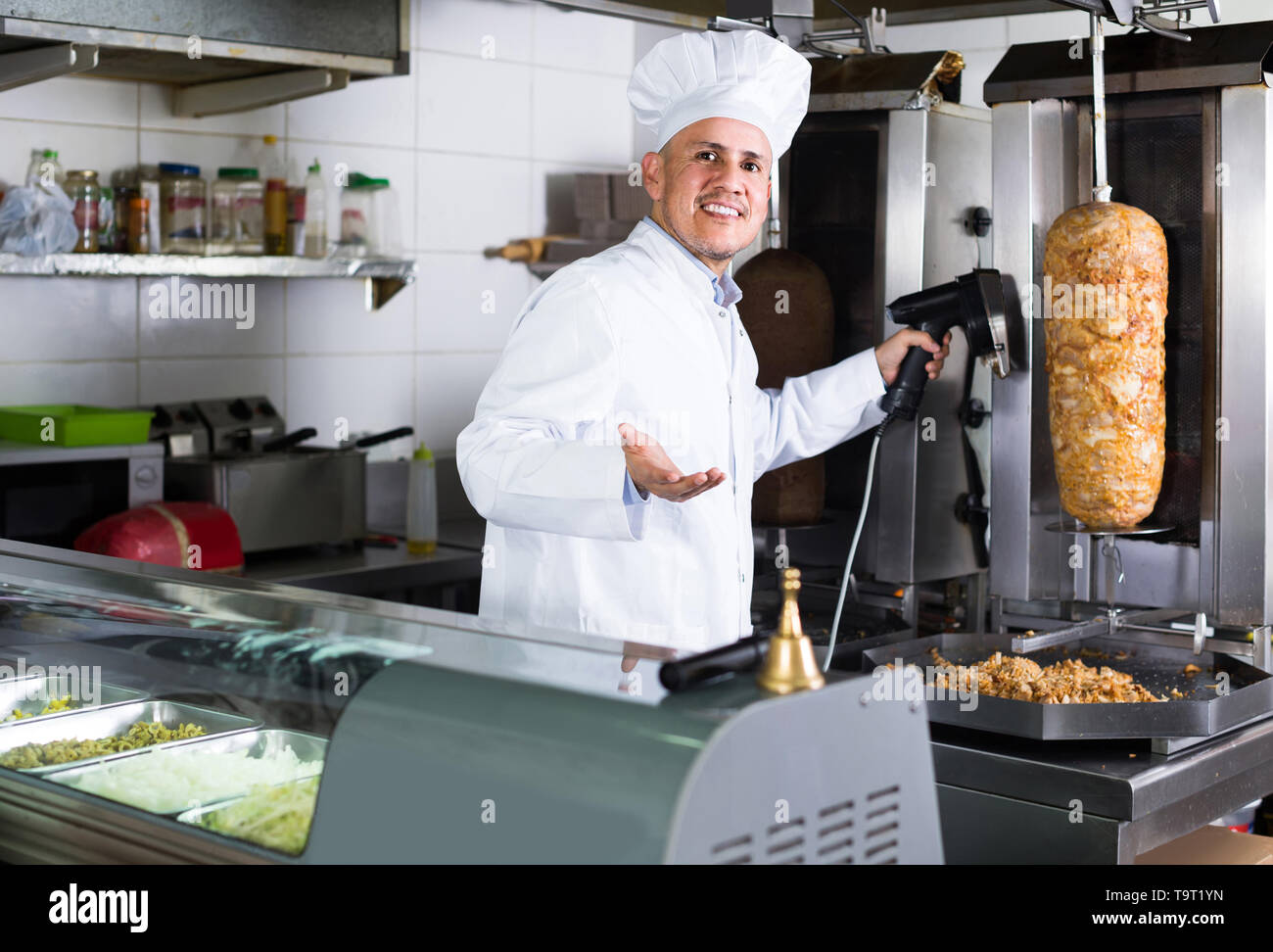 Happy American Mature Man Chef Wearing Uniform Cutting Meat For