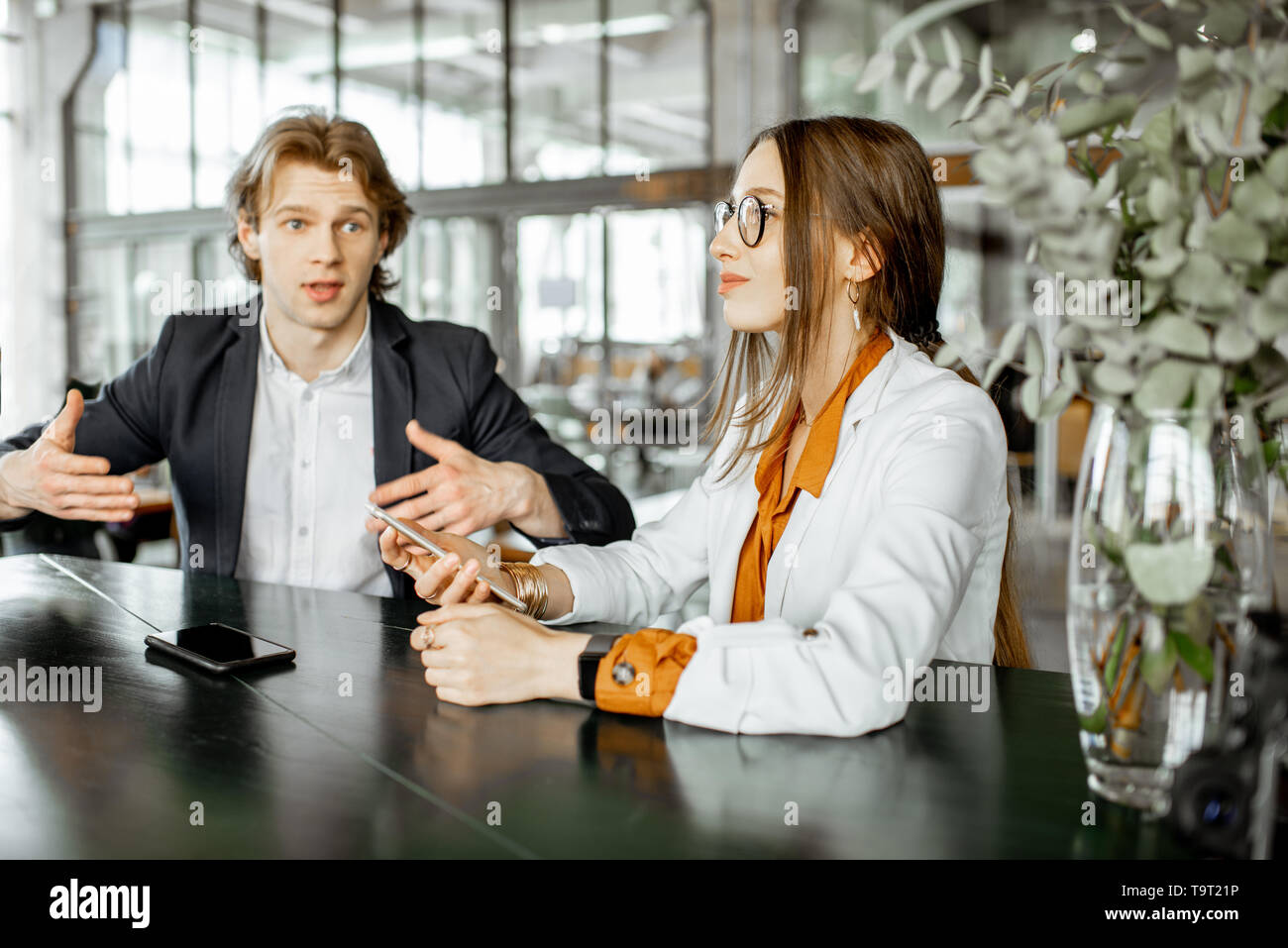 Young man and woman having business conversation while sitting together ...