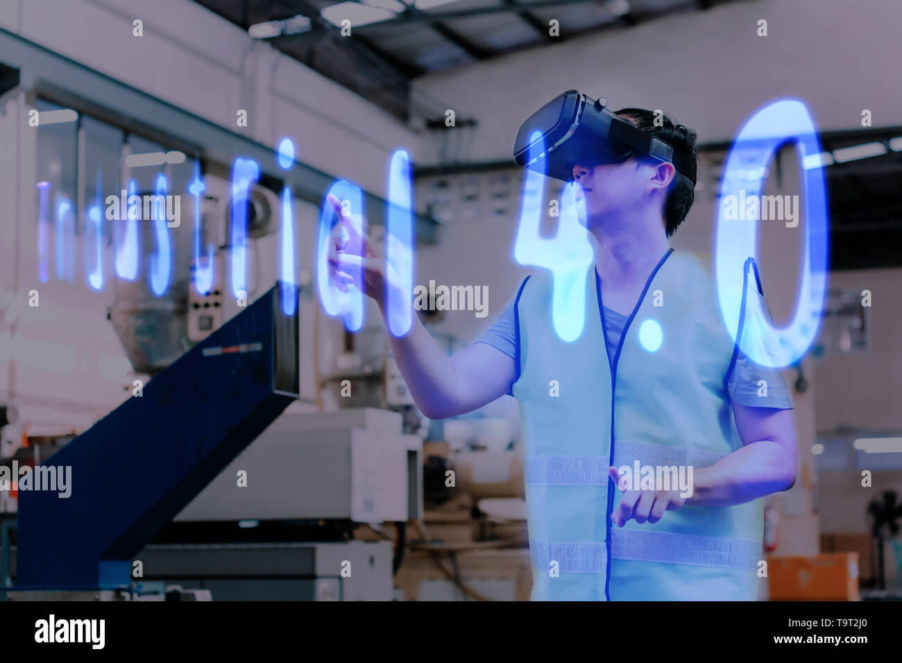 Factory and manfacturing engieering worker wearing VR goggle headset touching Industrial 4.0 text on virtual reality Stock Photo