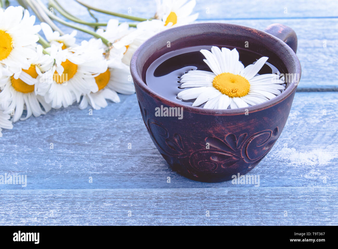 Cup of chamomile tea with a bouquet of daisies on a wooden blue ...