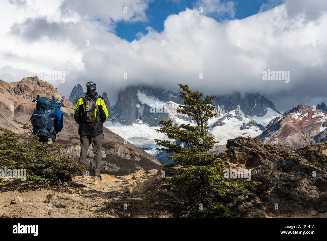 Two hikers view Mount FItz Roy in the clouds in Los Glaciares National ...
