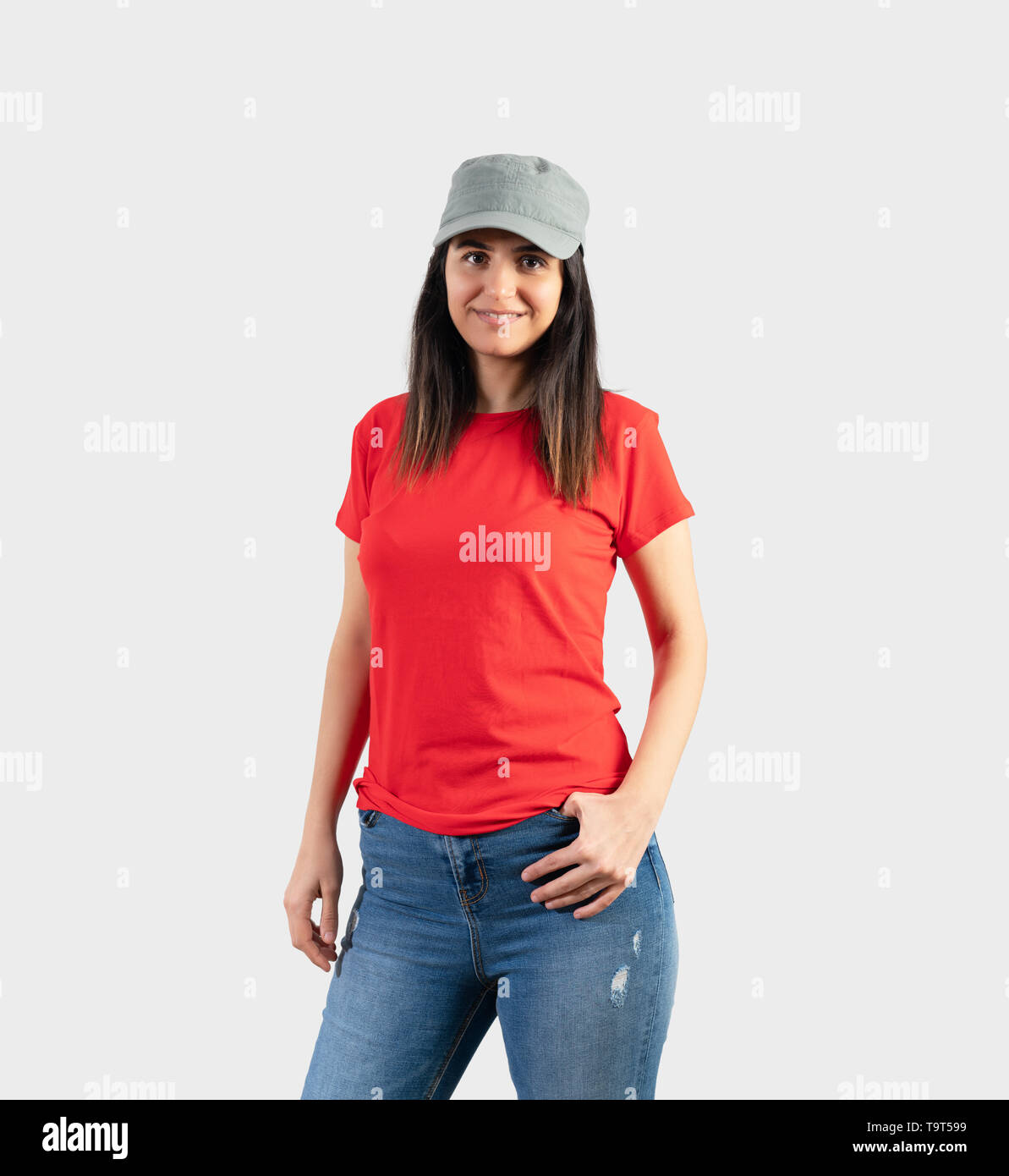 Young girl wearing blank red t-shirt, cap  and blue jeans. Grey wall background . Stock Photo