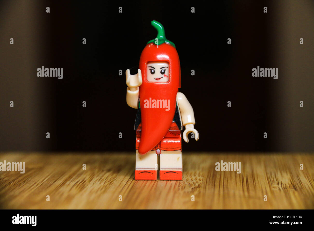 A red pepper standing and waving to the camera on a wood table. Stock Photo