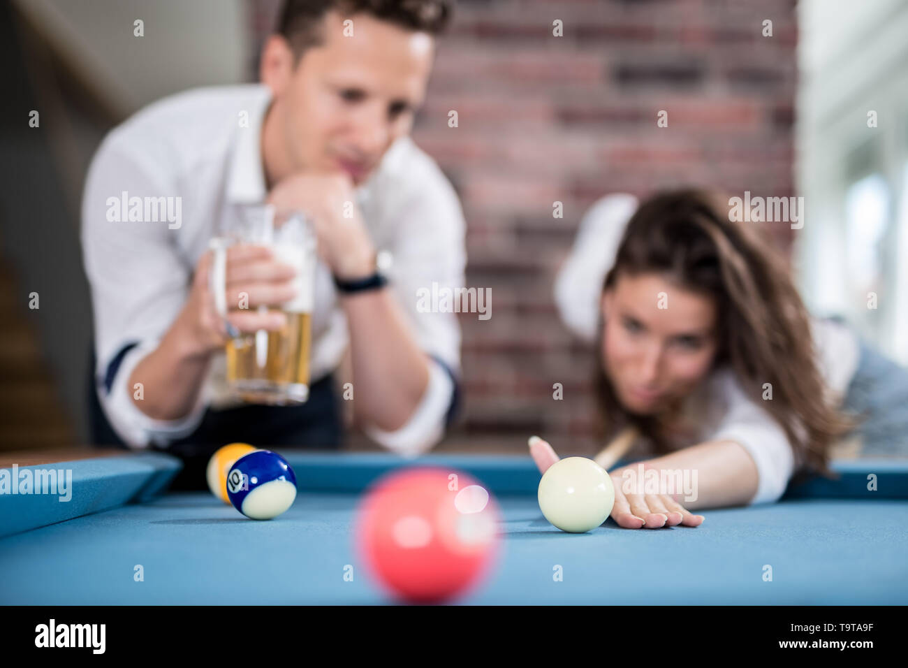 Couple playing snooker game and drinking beer. Stock Photo