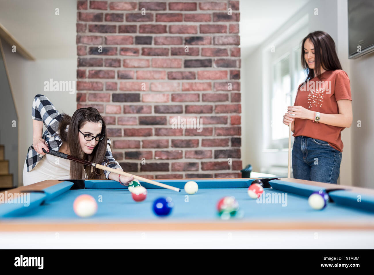 Two female students playing billiard game. Stock Photo