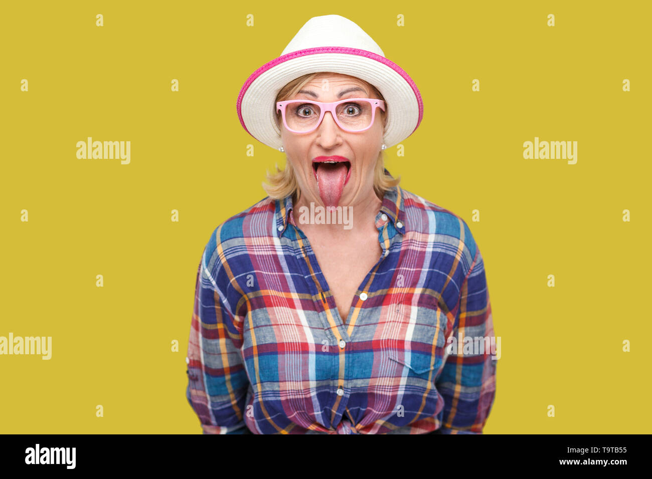 Portrait of funny surprised modern stylish mature woman in casual style with  hat and eyeglasses standing tongue out, looking at camera with big eyes  Stock Photo - Alamy
