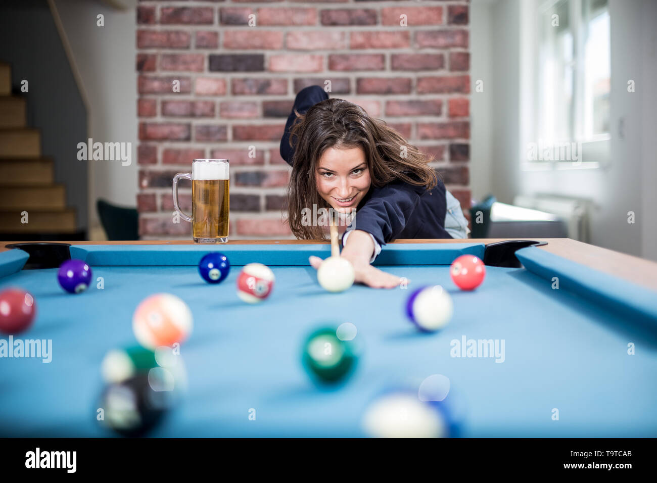 Portrait of pretty young female playing billiards. Stock Photo