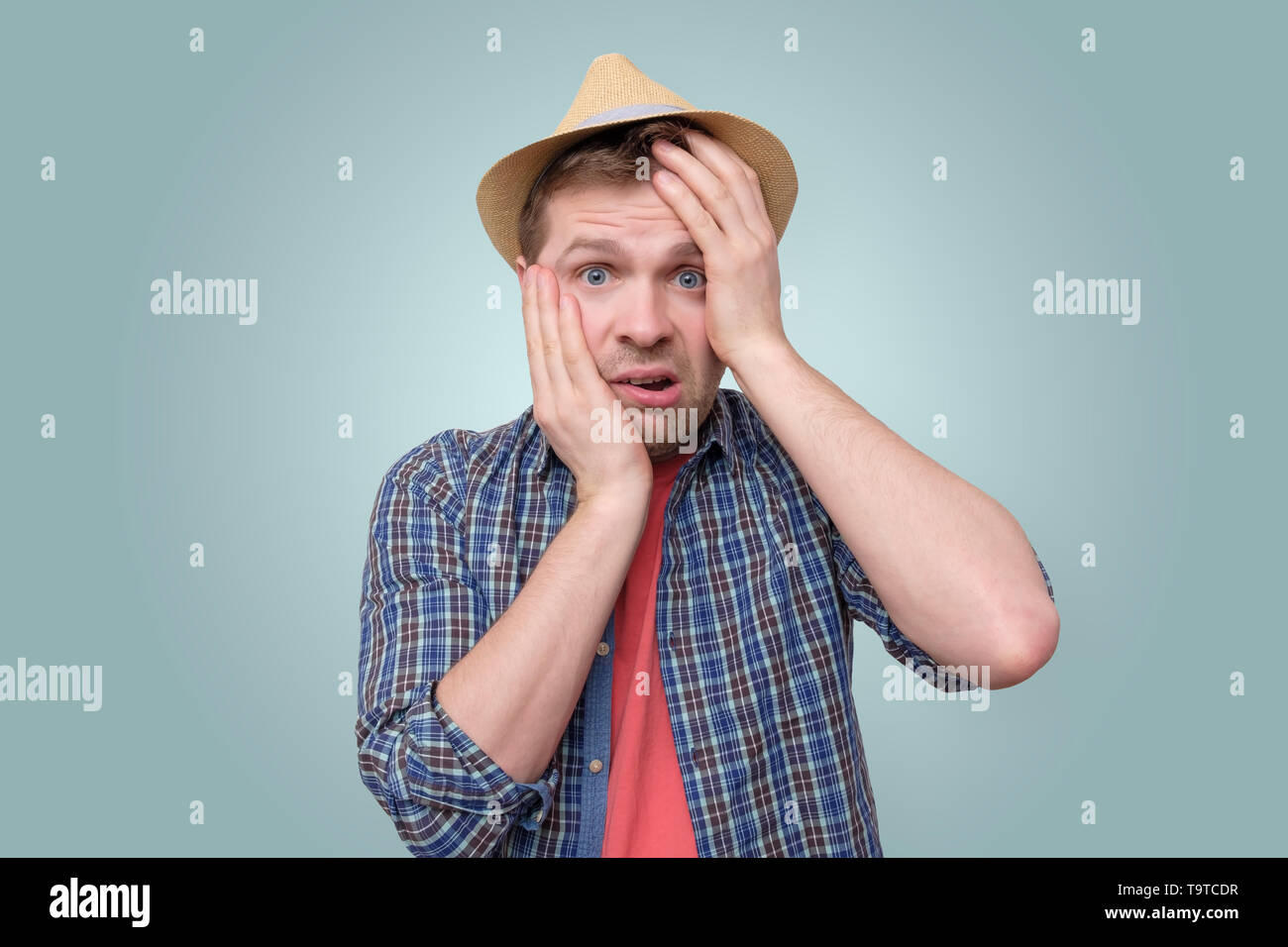 Young man puts hand to face in shame and frustration. Stock Photo