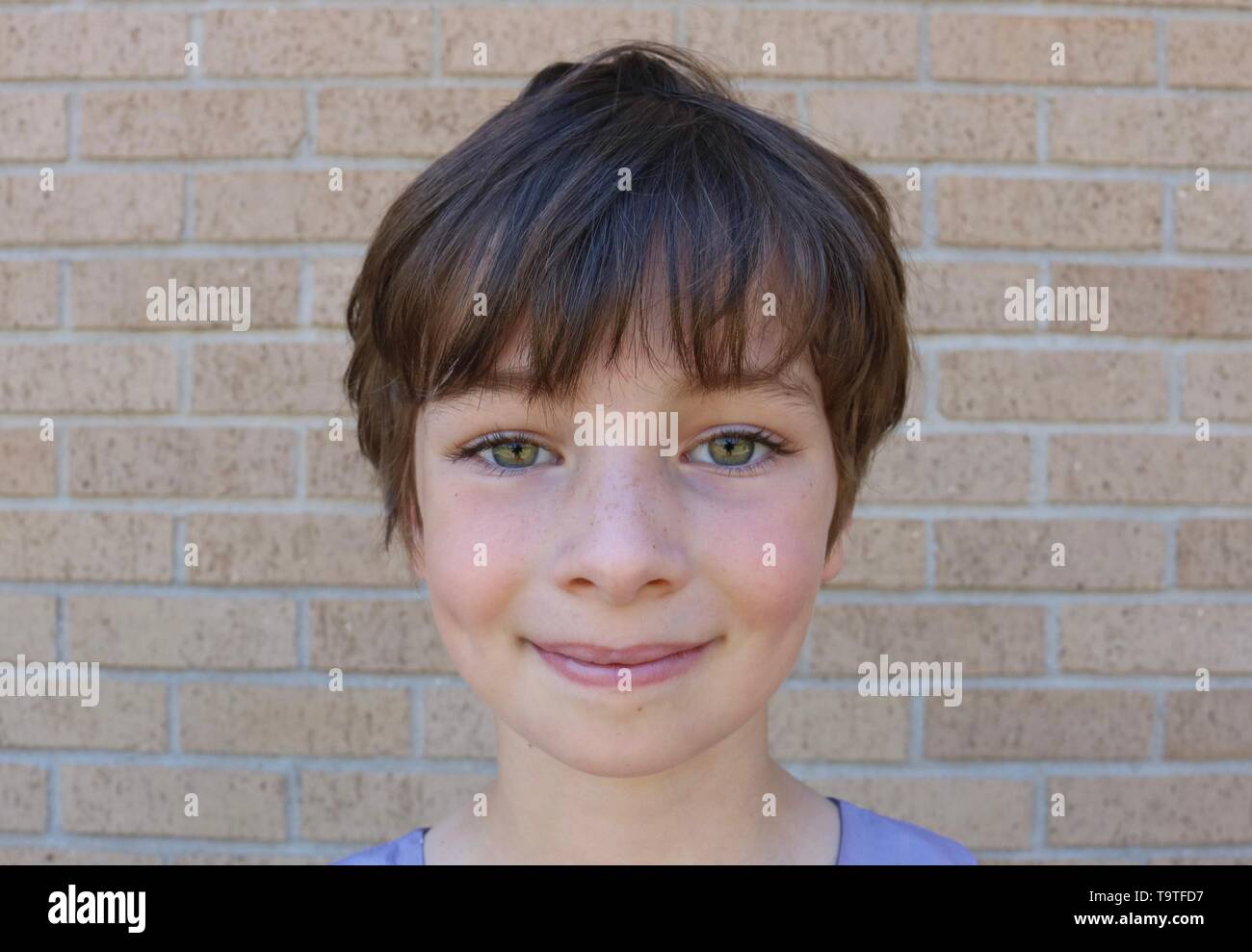 Face of young child with stunning hazel eyes, short brown pixie hair and dimples Stock Photo