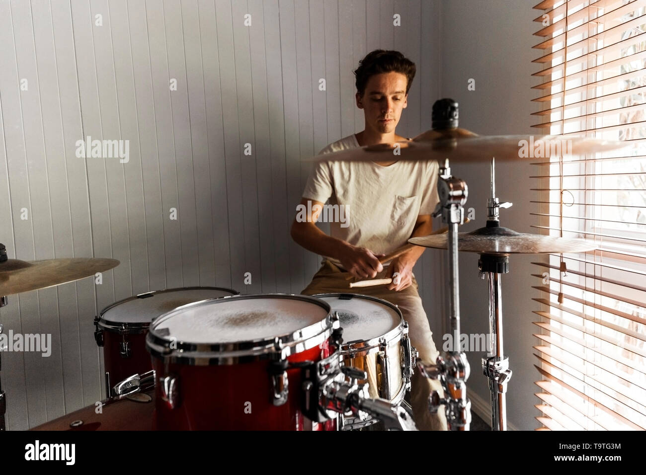 Enthusiastic drummer playing rock beat on practice drum kit Stock Photo