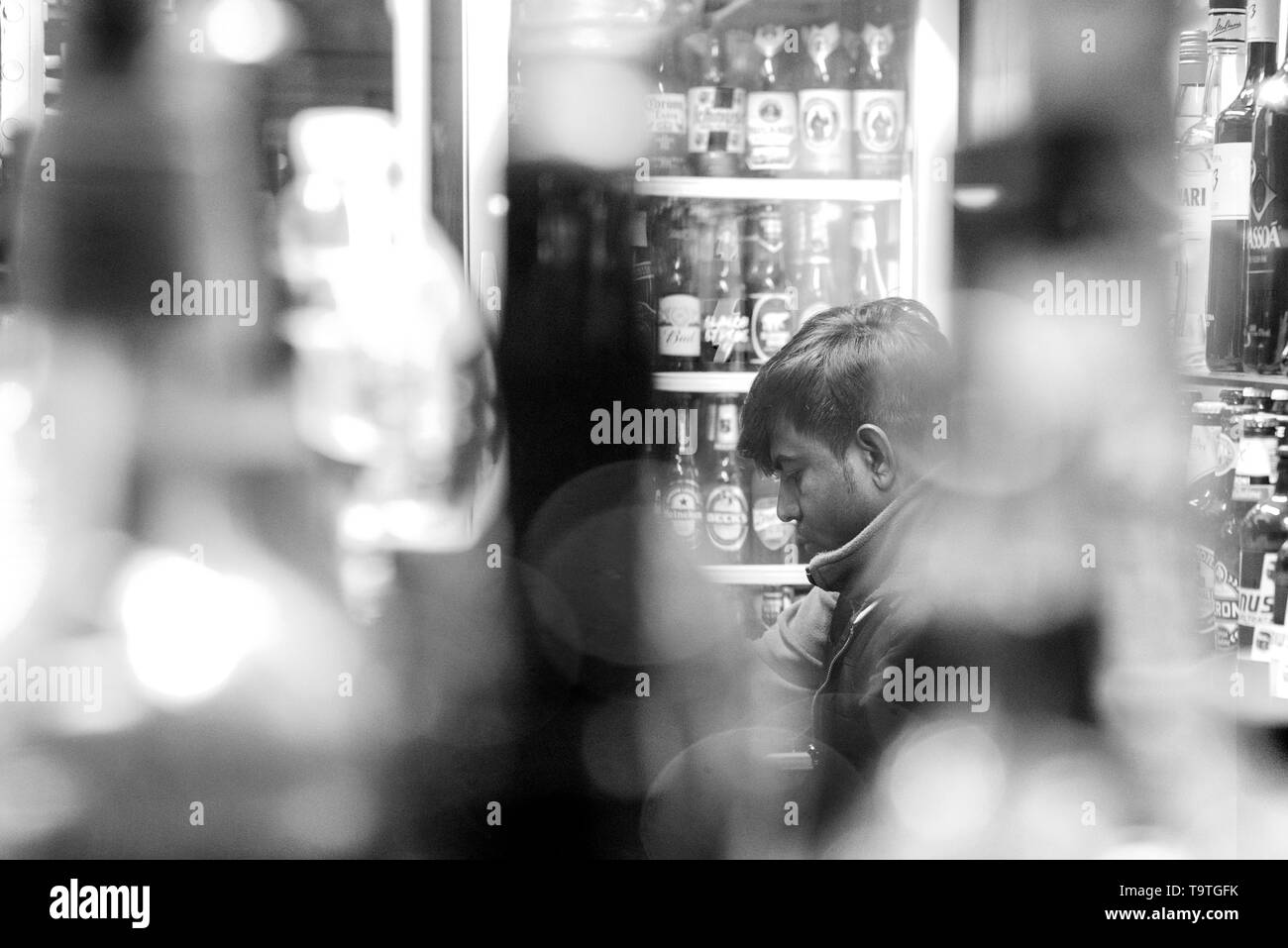 man sitting  among bottles with bokeh, in black and white Stock Photo