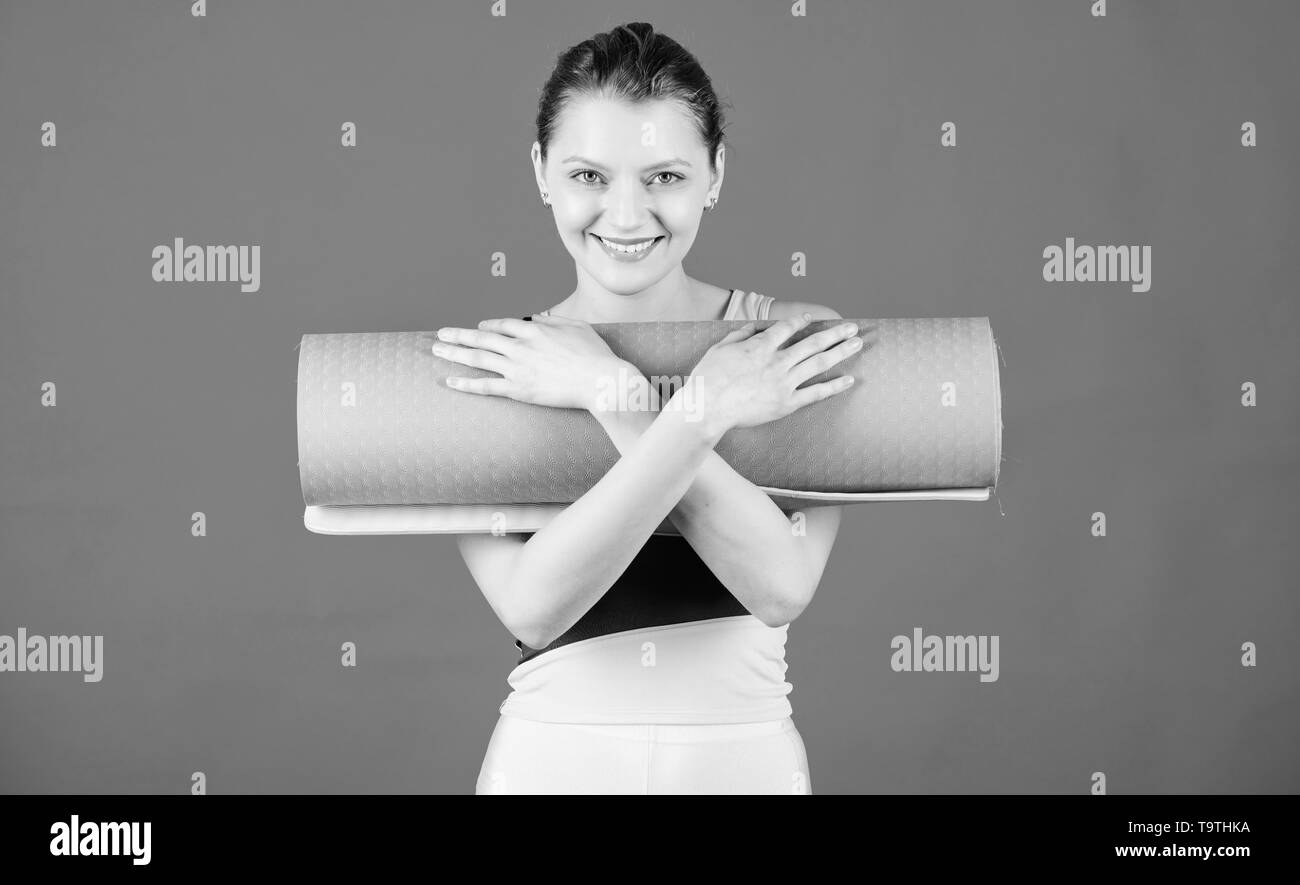 Girl smiling slim fit athlete hold fitness mat. Fitness and stretching