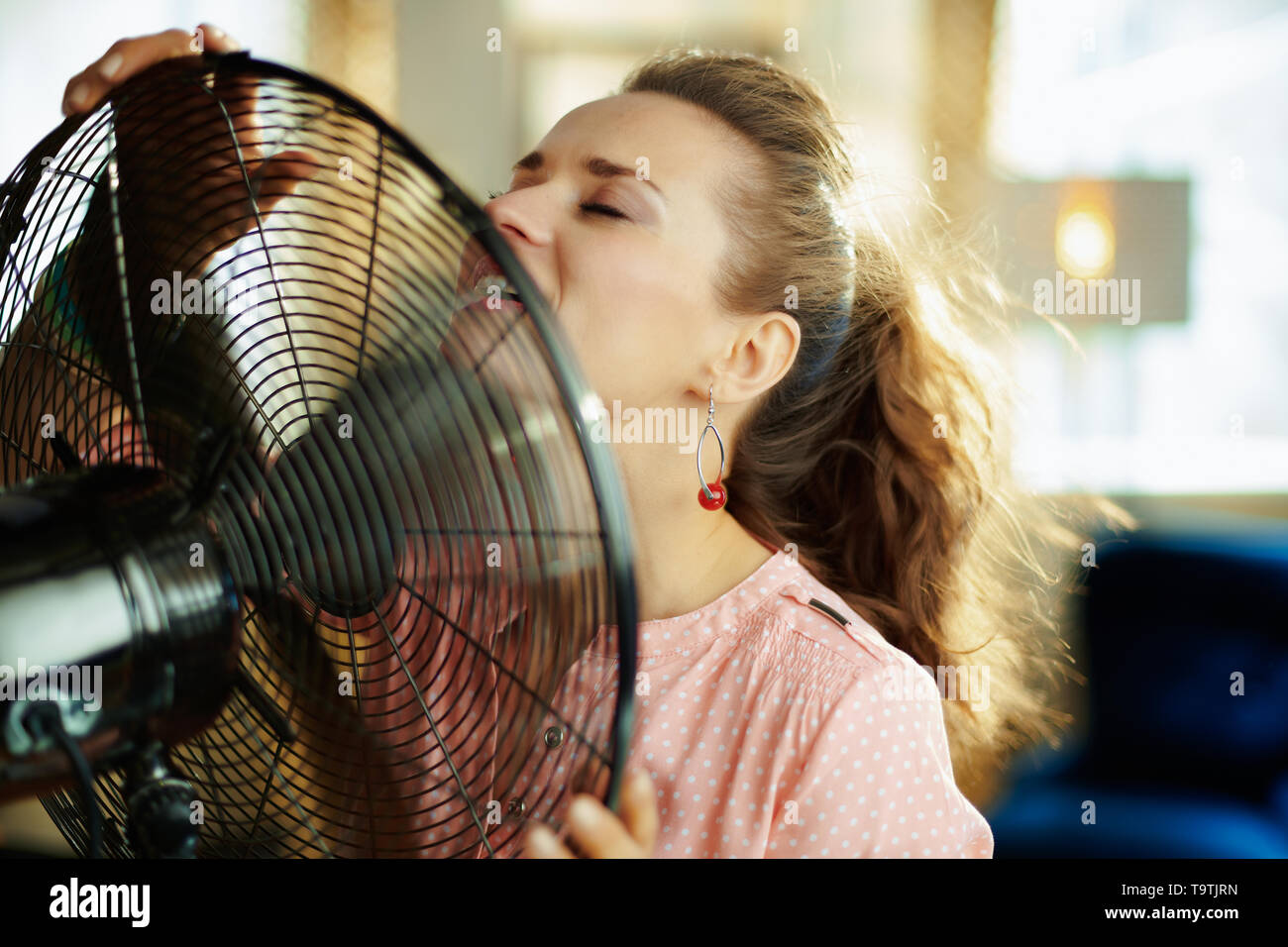 elegant woman at modern home in sunny hot summer day cooling down using