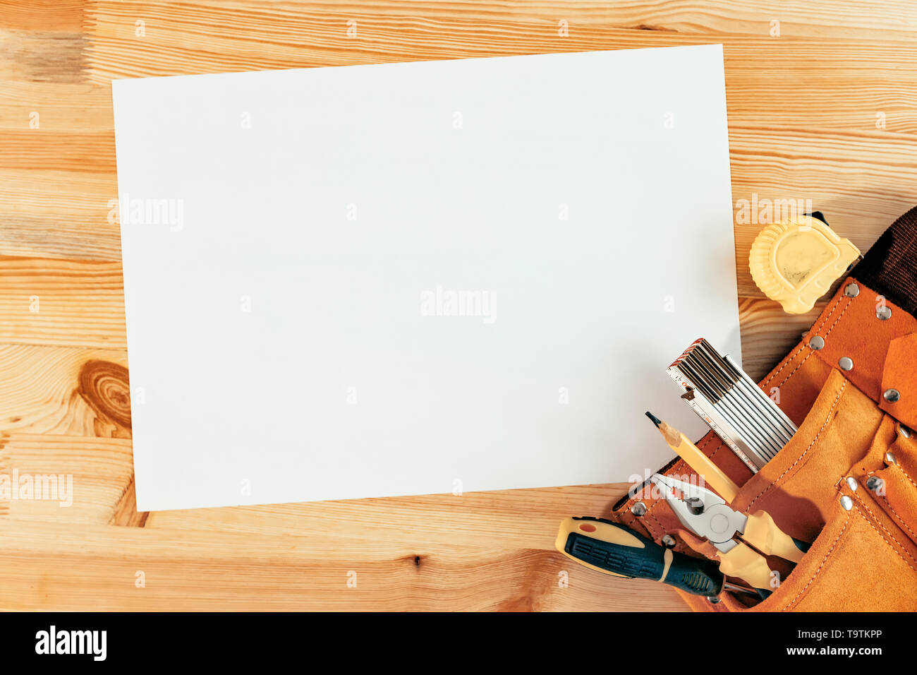 Empty paper as mock up copy space on woodwork desk with tool belt, top view Stock Photo