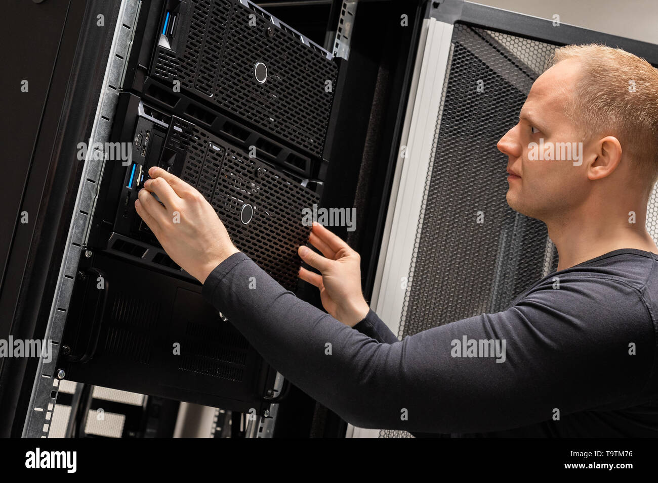 IT Professional Working With Servers In Large Datacenter Stock Photo