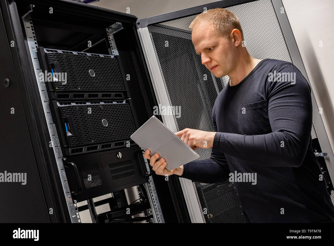 IT Engineer Holding Digital Tablet Analyzing Servers in Datacenter Stock Photo