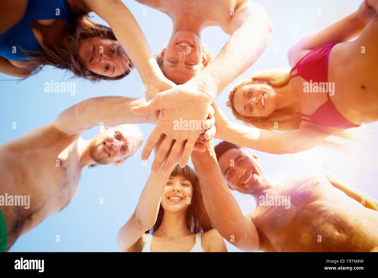 Happy group of friends give five in circle under the sun Stock Photo