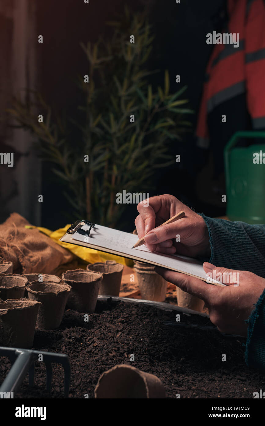 Gardener writing notes on clipboard note paper, preparation for seed ...