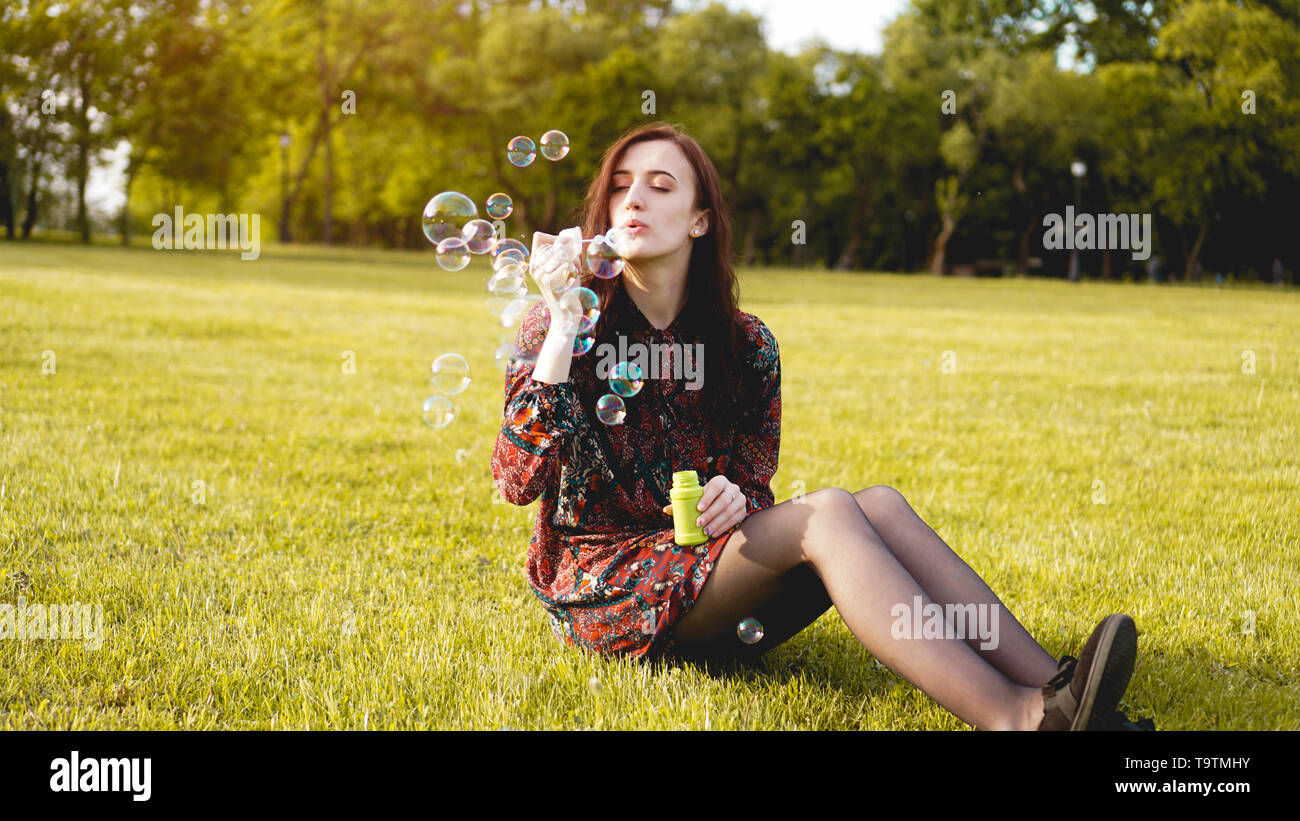 Romantic portrait of young woman with soap balloons. Sunny Valley on a summer day Stock Photo