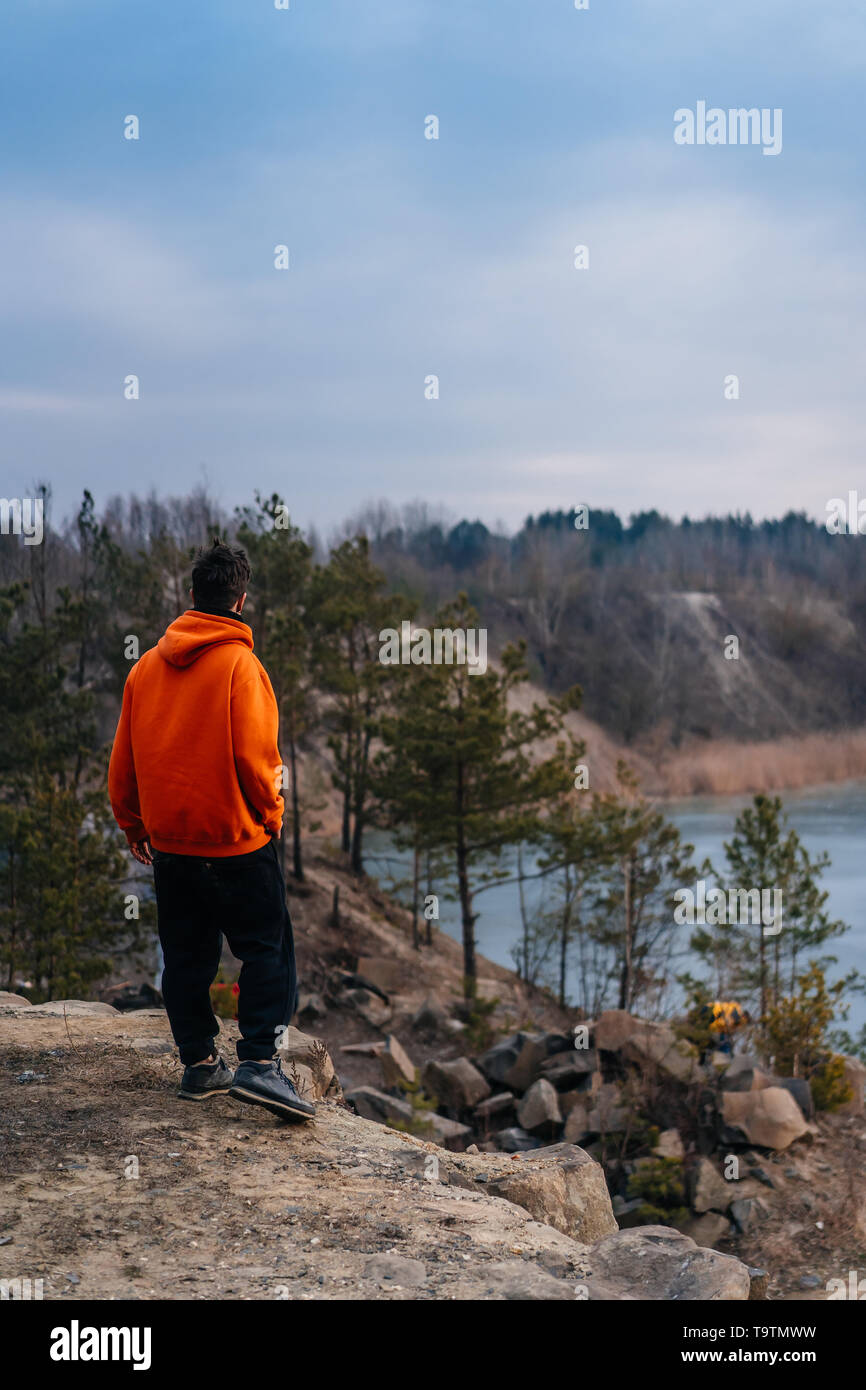 A young man standing on the edge of a cliff poses for the camera Stock ...