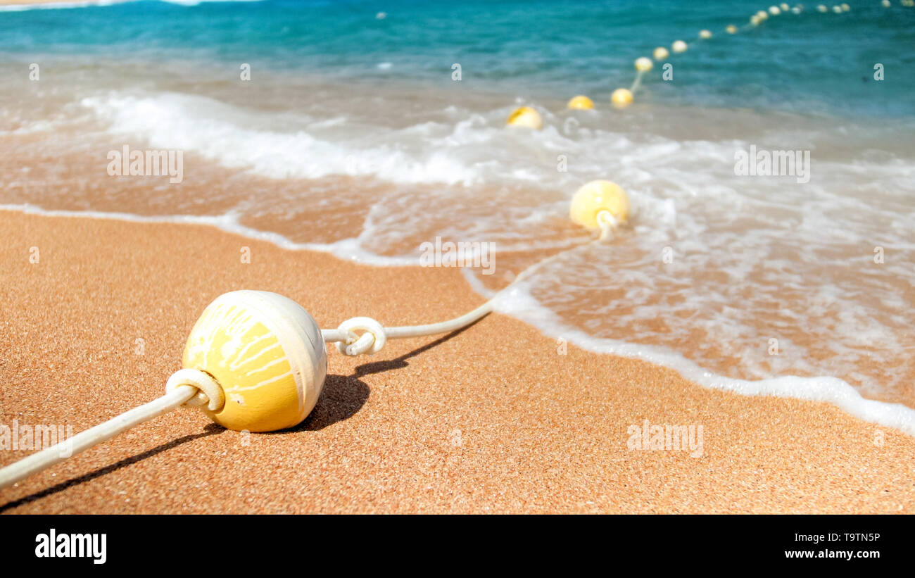 Closeup image of plastic floating buoys connected in line by rope lying ...