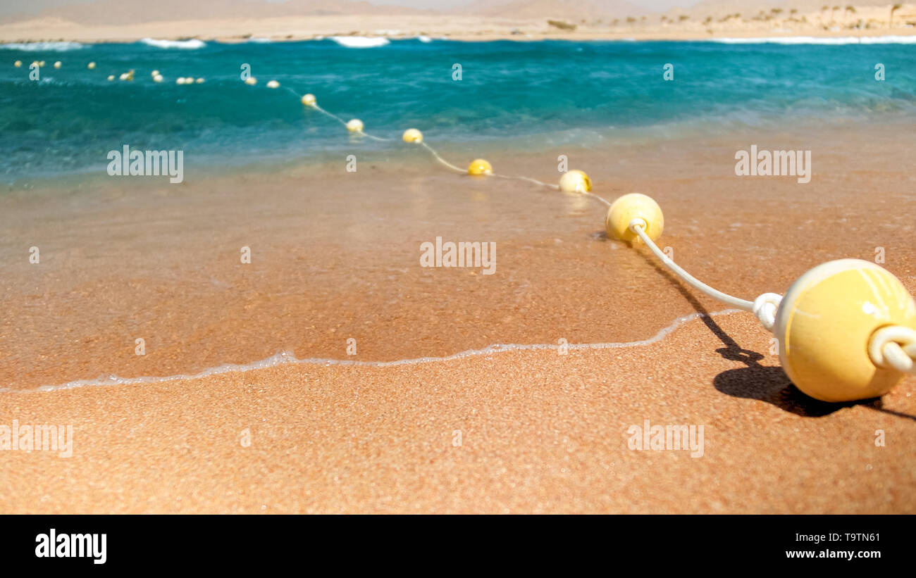 Closeup image of plastic floating buoys connected in line by rope lying ...
