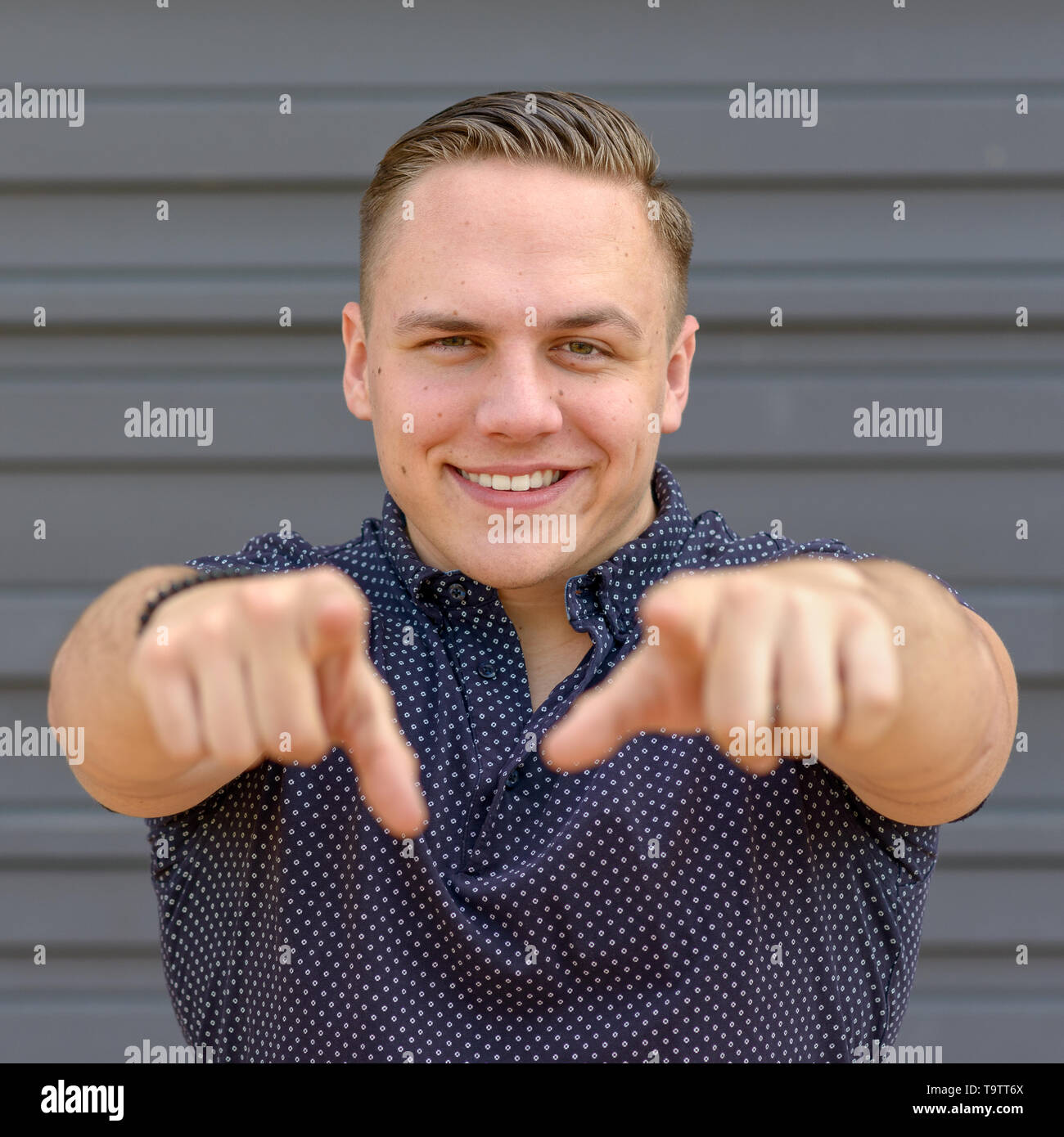 Smiling happy young man gesturing pointing to the camera with both hands in a square Format with copy space Stock Photo