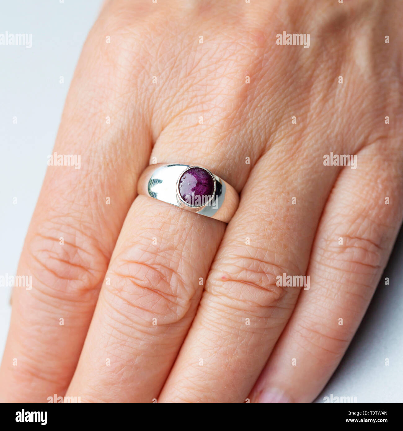 Silver ring with ruby star gemstone caboshon on female hand Stock Photo