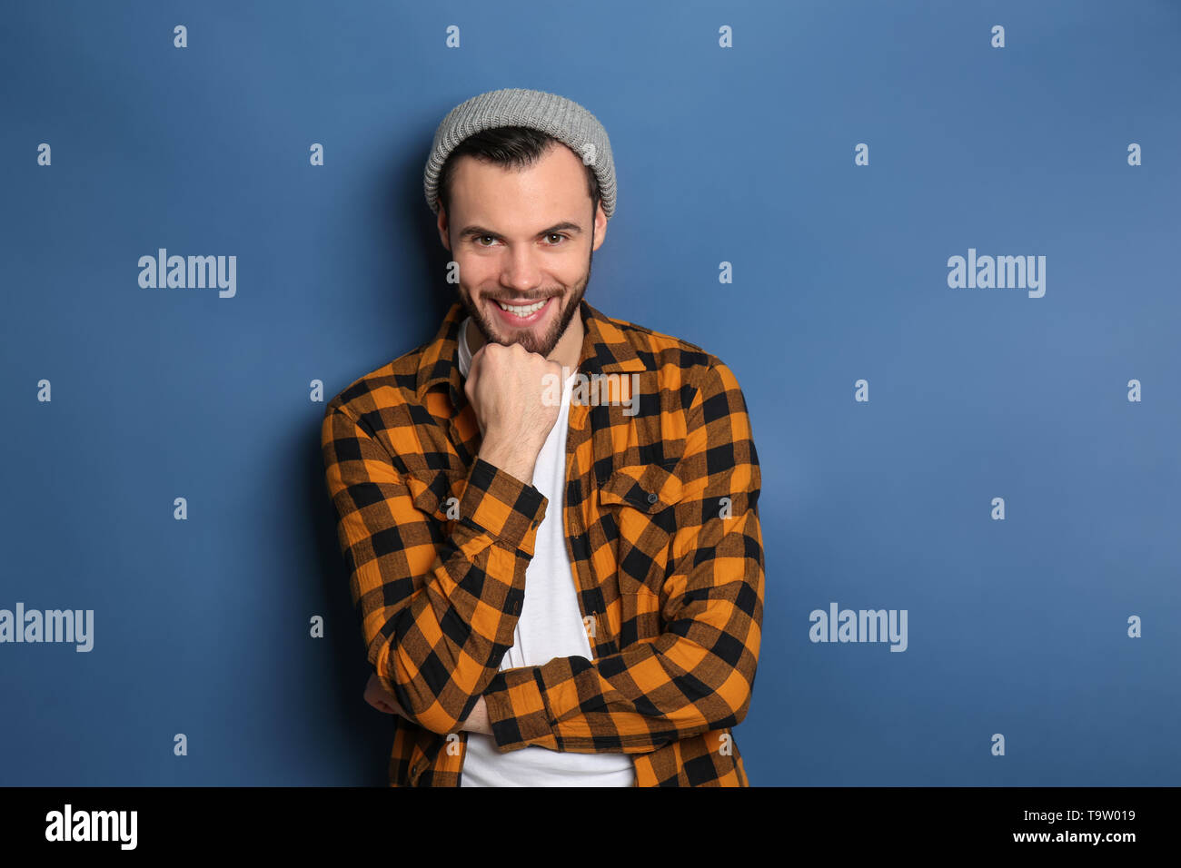 Fashionable young man in checkered shirt on color background Stock — free download