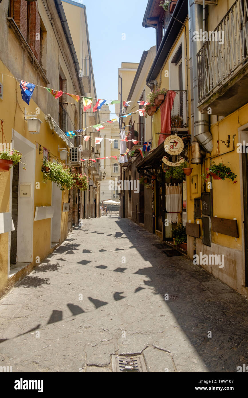 An alley shows the character of the historical center of Benevento. Triangular country flags and flowers and plants cheer up this beautiful place. Stock Photo