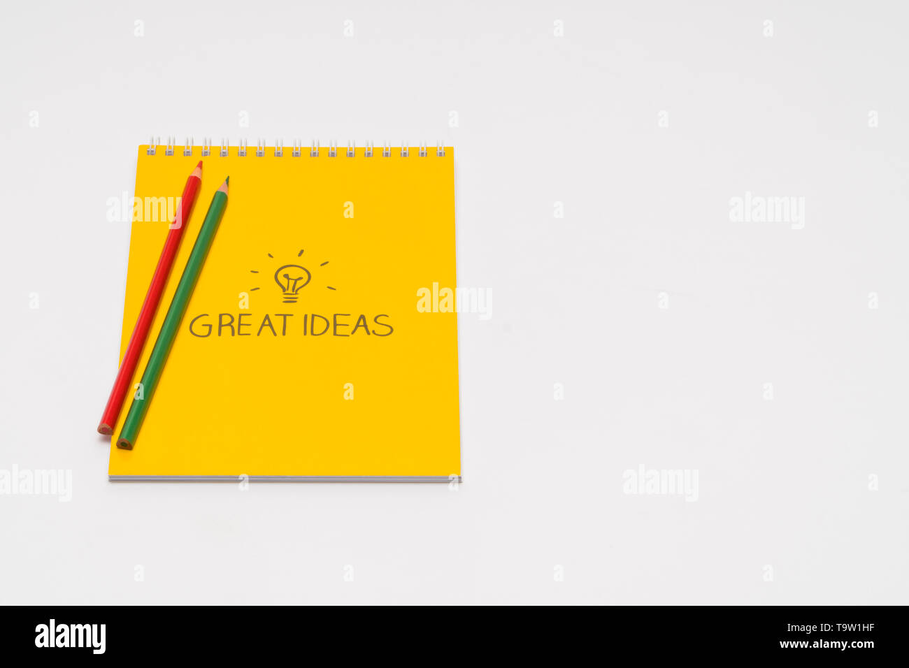 yellow notepad with colored pencils on white background, isolated. back to school. great ideas Stock Photo