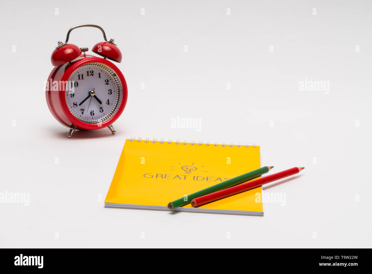 alarm clock with notepad and colored pencils on white background, isolated. back to school. great ideas Stock Photo