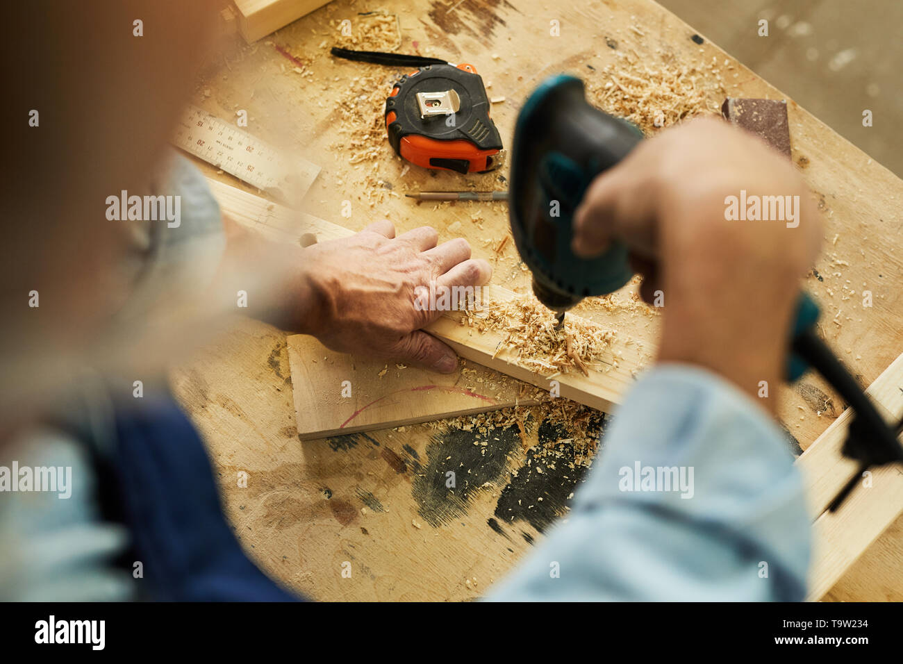 Above view of unrecognizable carpenter drilling wood while working in ...