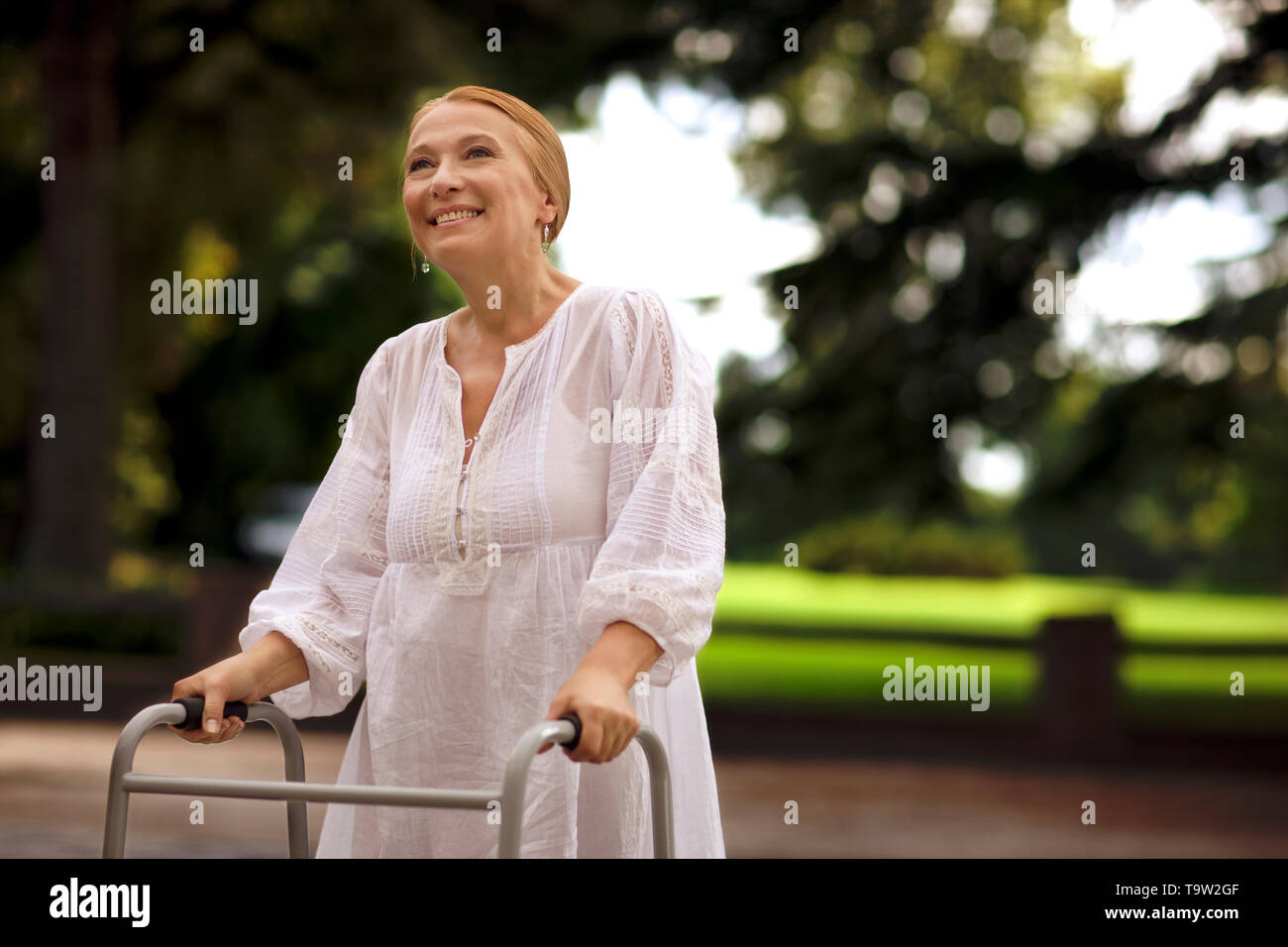 Elderly woman using a walker outdoors. Stock Photo