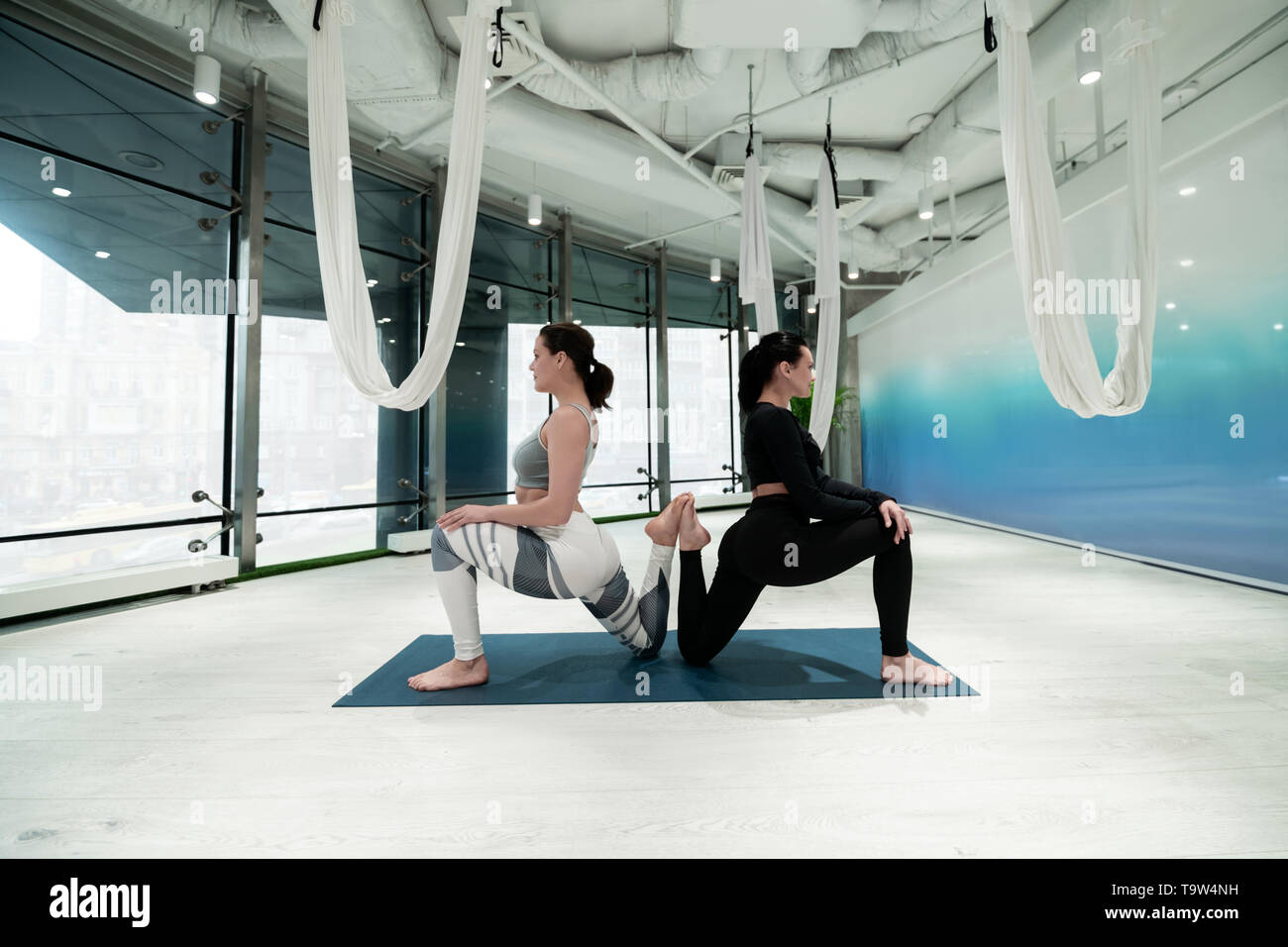 Women in leggings doing yoga together in spacious room Stock Photo