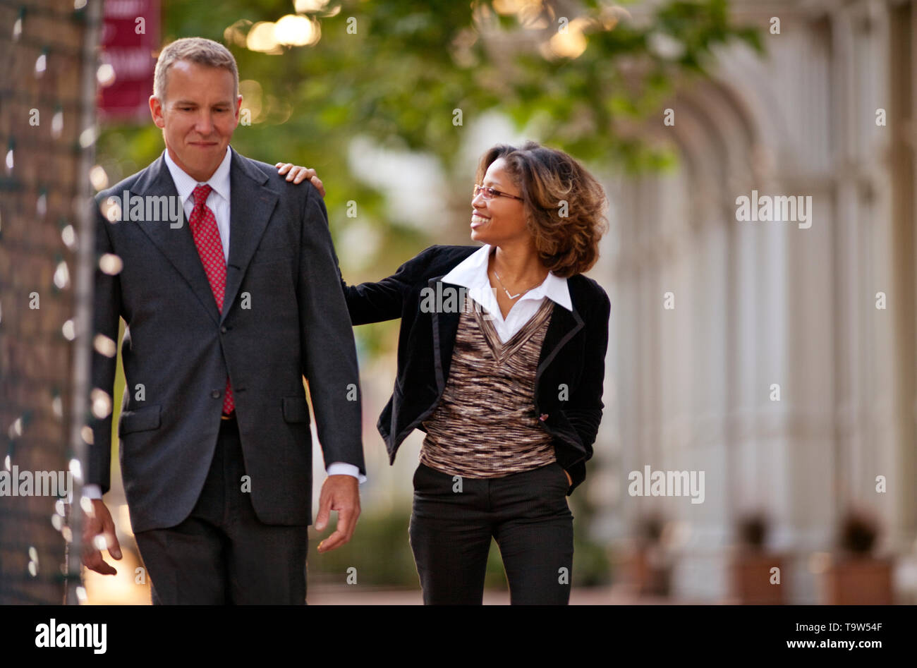 Co-workers walking together happily on sidewalk. Stock Photo