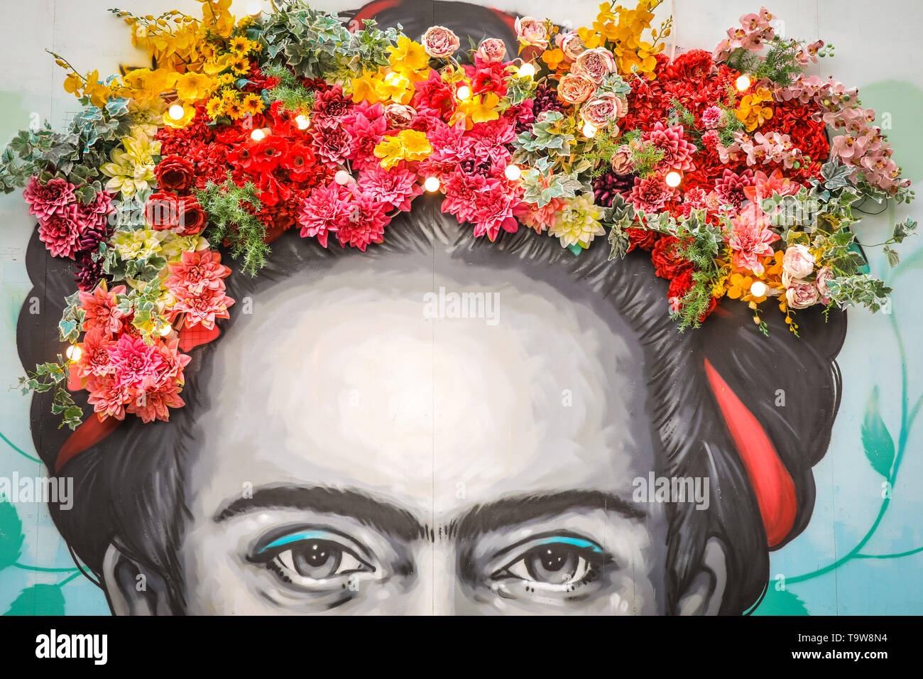 Belgravia, London, UK, 20th May 2019. An existing installation by Moyses Stevens florial artistry, which is again on display with other new floral displays in Eccleston Yards. The work shows a floral crown above a painting of Frida Kahlo by artist Zabou, called 'Frida with Flowers' (in situ since 2018).  Belgravia's fourth annual floral festival coincides with the RHS Chelsea Flower Show in neighbouring Chelsea. Credit: Imageplotter/Alamy Live News Stock Photo