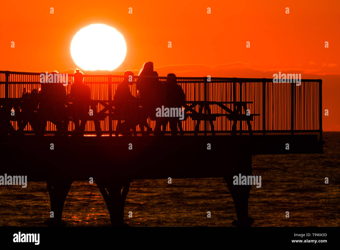 Aberystwyth Wales UK, Monday 20 May 2019  UK Weather: People  on the pier enjoying  a drink and the view of the glorious golden sunset over Cardigan Bay, at the end of a day of warm spring sunshine in Aberystwyth Wales. The weather is set fine for the coming days , with extended spells of warm sunshine  photo credit: Keith Morris / Alamy Live News Stock Photo