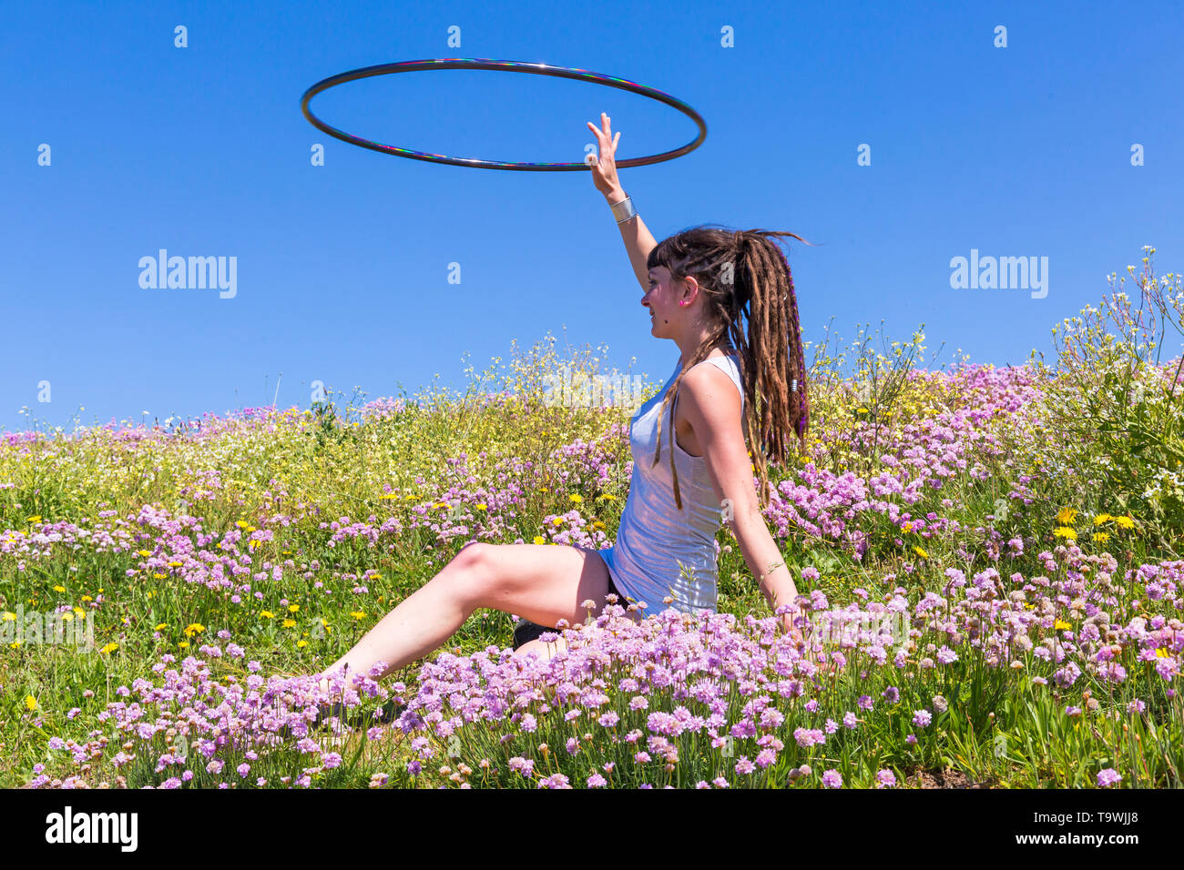 Southbourne, Bournemouth, Dorset, UK. 21st May, 2019. UK weather: lovely warm sunny morning as Lottie Lucid performs her hula hooping routine on the seafront cliffs at Southbourne among the wildflowers, Sea Thrift, Armeria maritime, enjoying the warm sunny weather in her mini dress. Credit: Carolyn Jenkins/Alamy Live News Stock Photo