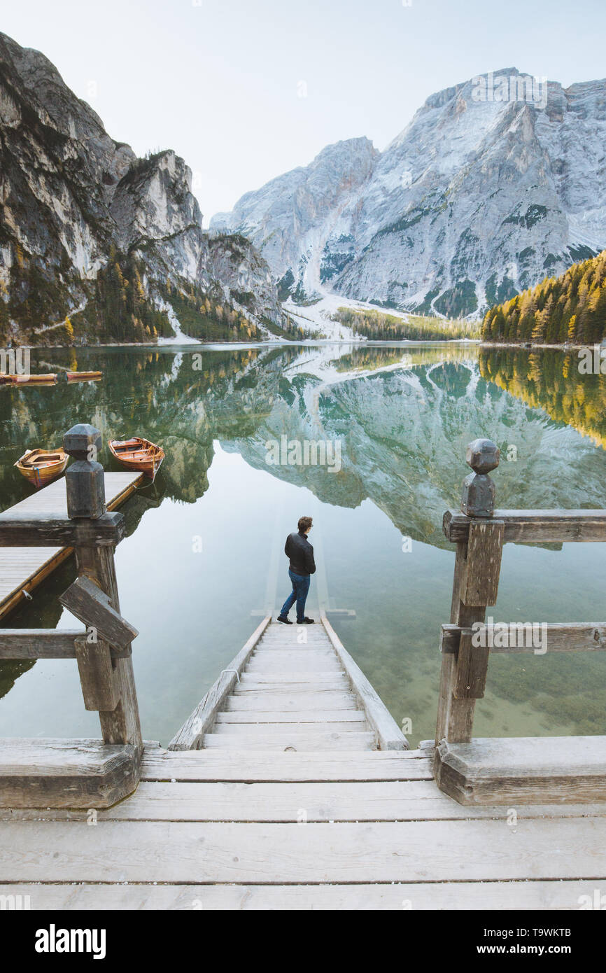 Beautiful view of a young man standing on wooden stairs watching the sunrise at famous Lago di Braies the Dolomites, South Tyrol, Italy Stock Photo