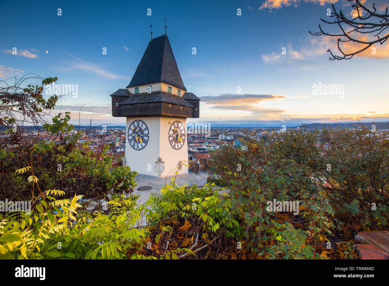 Classic panorama view of the historic city of Graz with famous Grazer Uhrturm clock tower in beautiful evening light at sunset, Styria, Austria Stock Photo