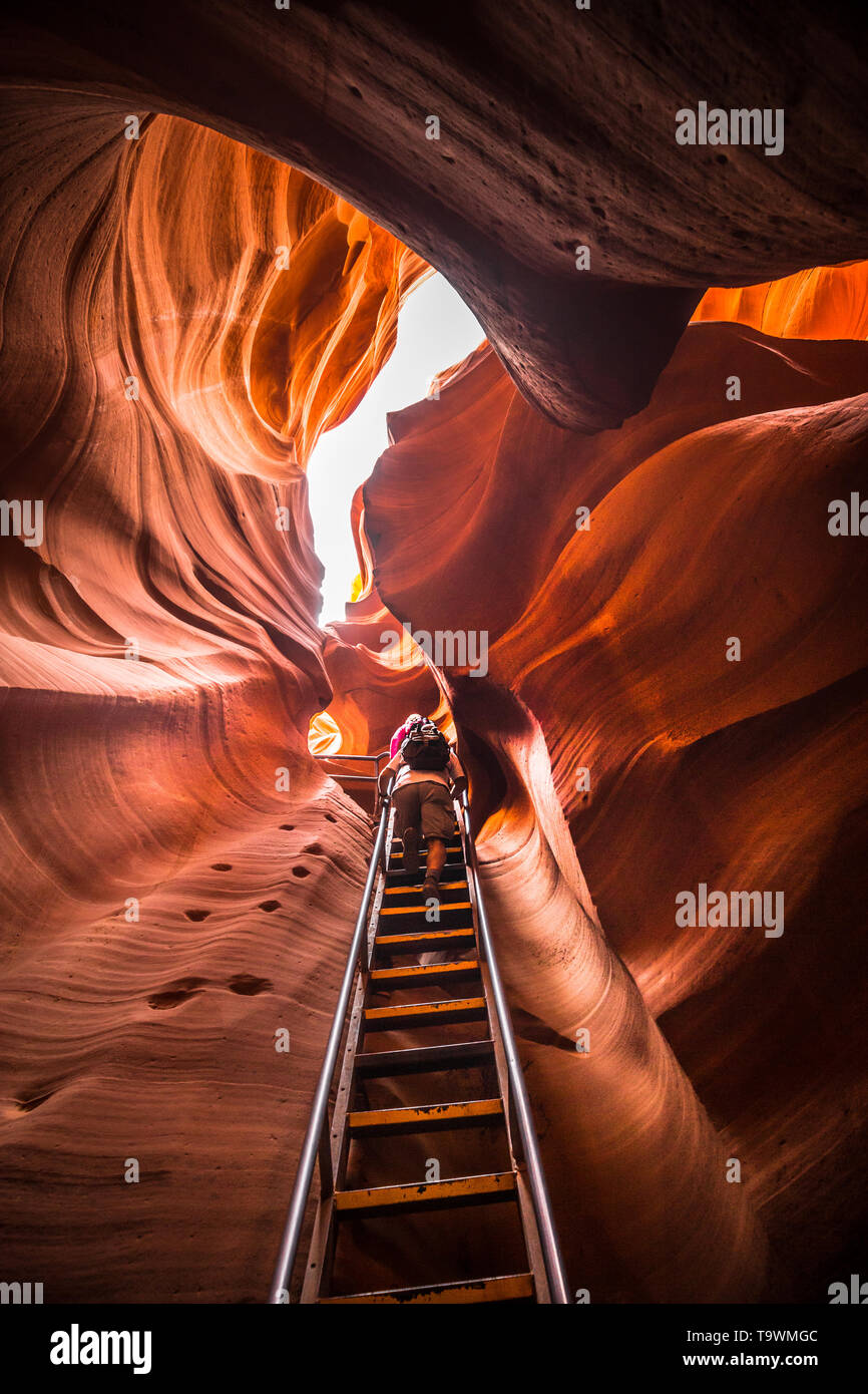 Amazing sandstone formations with hikers ascending a steep ladder in famous Antelope Canyon on a sunny day near the old town of Page at Lake Powell, A Stock Photo